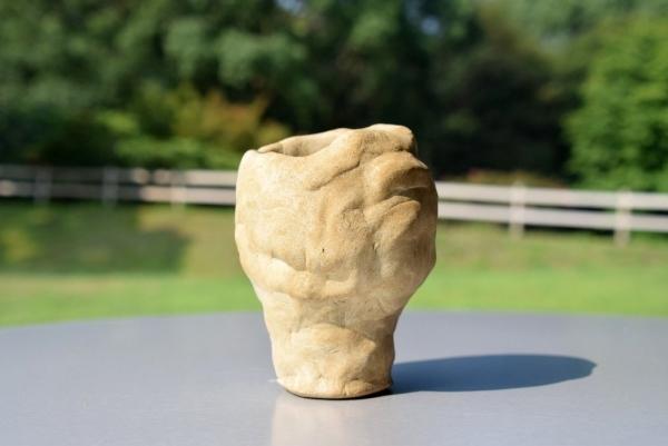 縦長の湯飲みのような形で、人の顔が右側を向いているように造られている土器完成品3の写真