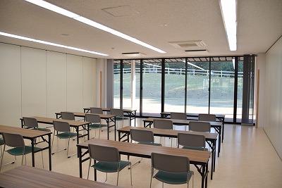 大きな窓を前方に、長机が2つずつ並んでそれぞれ椅子が2脚ずつ設置されている実習室Bの写真