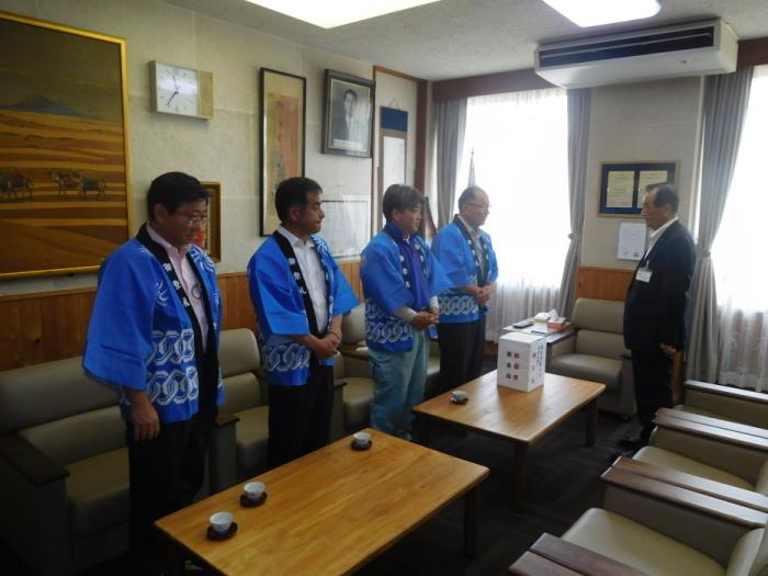 市長の机の上に義援金箱を置き挨拶をしているハッピ姿の上陽祇園祭実行委員会の男性4人の写真