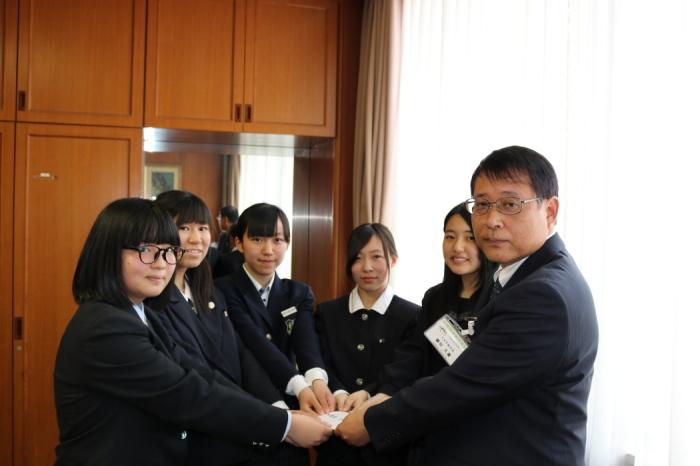 代表の女子学生5名と副市長が寄付金を手に取っている写真