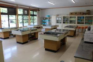 ガスコンロ、流し台がついた調理台の奥に食器棚が設置してある調理室の写真