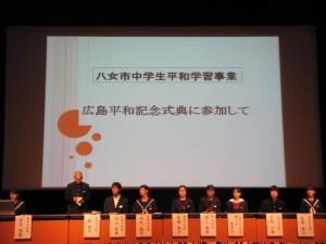「広島平和記念式典に参加して」と書かれたスクリーンの前で横1列に並んで着席している生徒達を写した写真