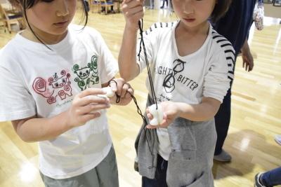 女の子たちが紐を通した勾玉を持っている写真