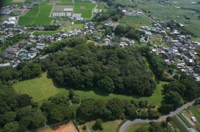 周辺に民家が密集しており、樹木に覆われている岩戸山古墳を上空から撮影した写真