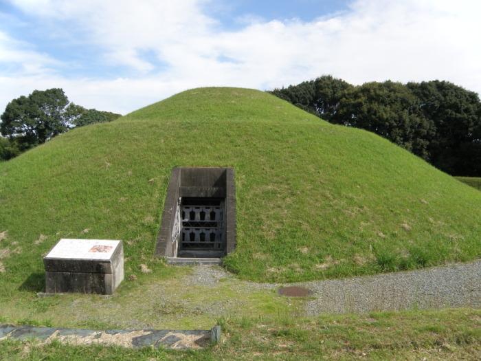 後方に樹木が植えられ、山の様に盛り上がっている中央に入口が設けられている弘化谷古墳の写真