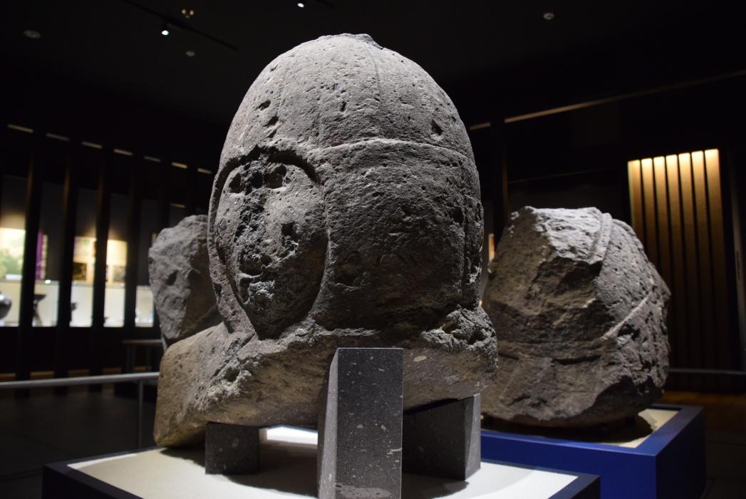 頭に頭巾を被ったような頭部だけの石人で、鼻が潰れている武装石人頭部を左側から撮影した写真
