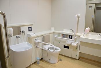 手すりや手洗い場が設置されている、車いすでも楽に入れるオストメイトトイレの写真