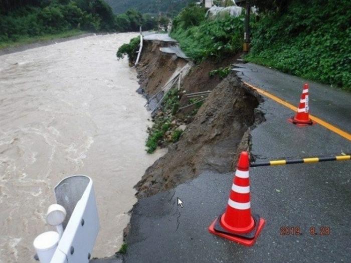 豪雨により道路の中央車線半分が崩れている被害の写真