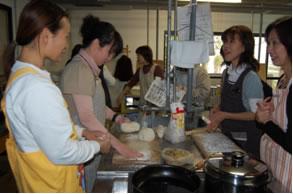 エプロンを着用した女性達が一緒に料理を作っている写真