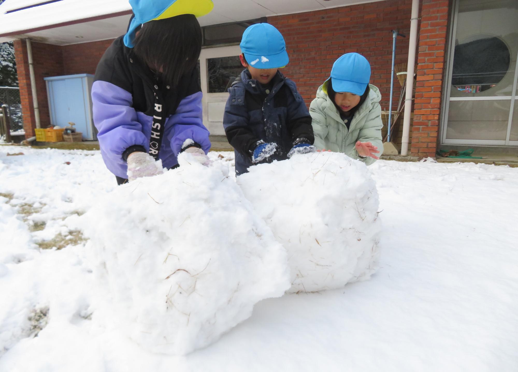雪だるまを作るこどもたちの写真