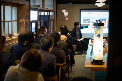 満席の中で報告をする様子